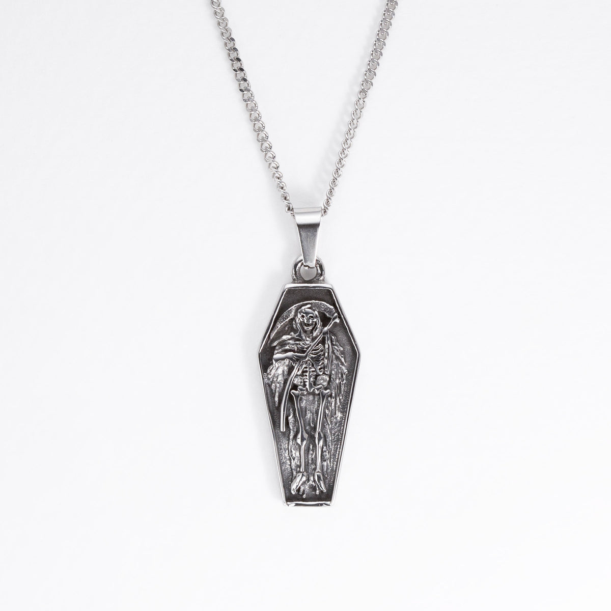 A silver coffin-shaped pendant necklace featuring an embossed skeleton figure, suspended from a silver box chain against a plain white background.