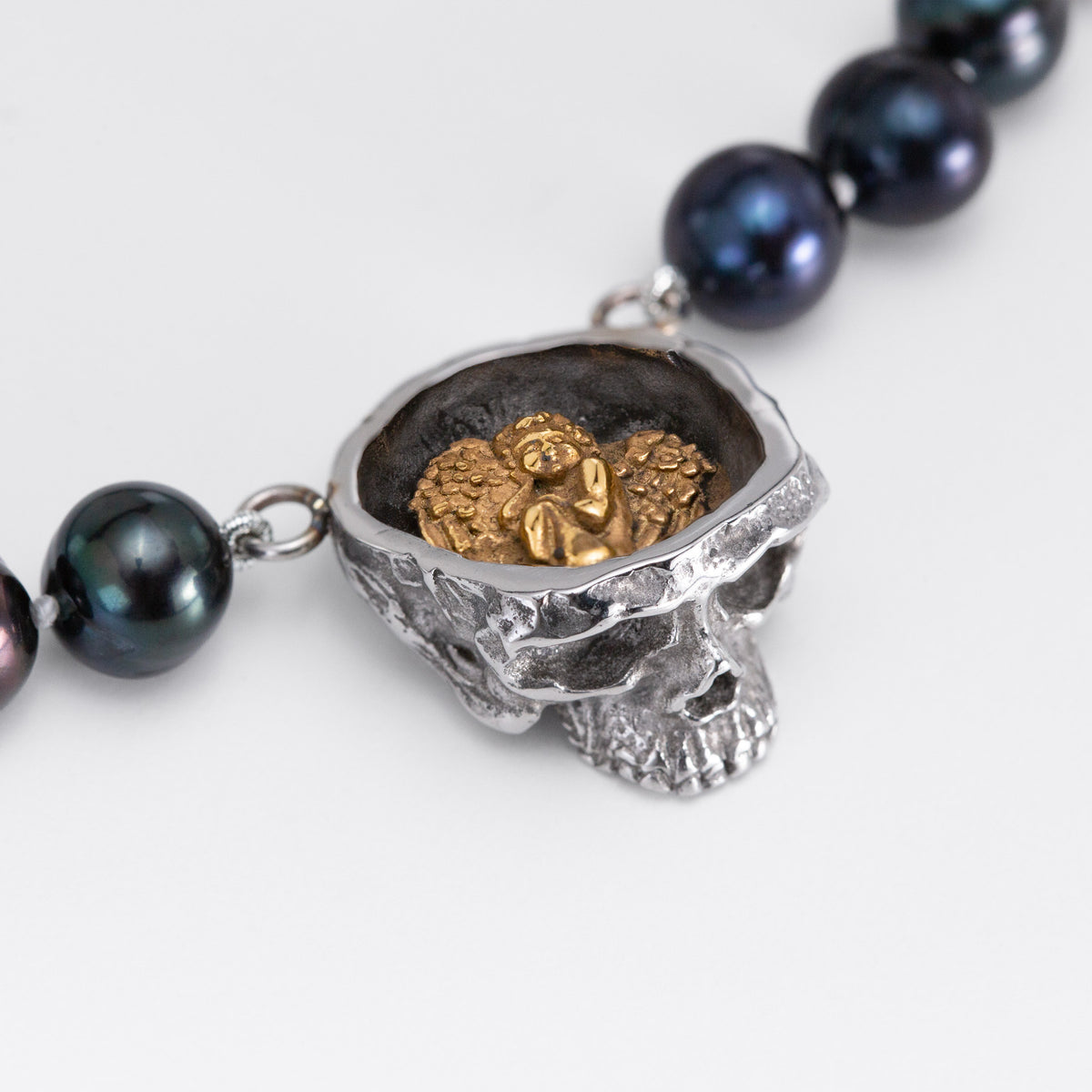Top view of the Nick Von K Rebirth skull pearls showing a gold-toned angel relief in a dark circular setting.