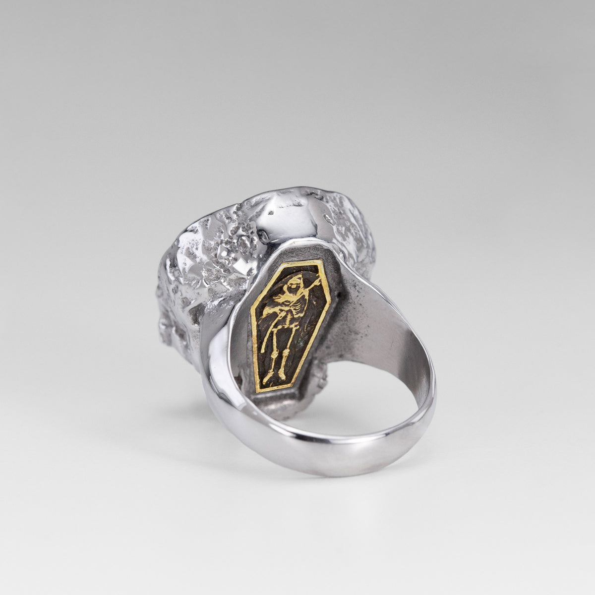 Rear view of the Nick Von K Rebirth skull ring showing a gold-outlined coffin with a skeletal reaper and scythe.