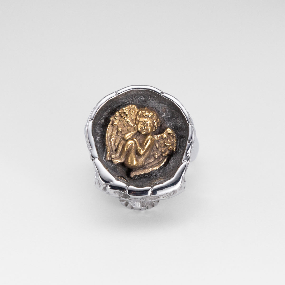 Top view of the Nick Von K Rebirth skull ring showing a gold-toned angel relief in a dark circular setting.