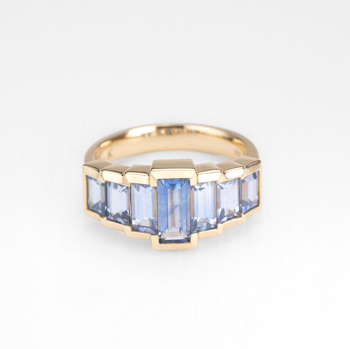 Gold ring with blue sapphires on a white background