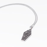 A silver coffin-shaped pendant necklace with engraved text and a sun motif, hanging from a silver chain against a plain white background.