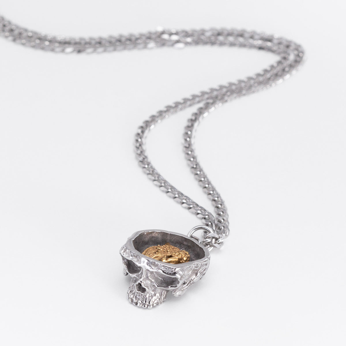 Angled front view of the Nick Von K Rebirth charm necklace with a sculpted skull pendant on a silver chain.