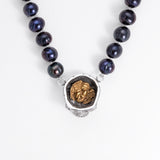 Top detail of the Nick Von K Rebirth pearl necklace showing a gold-outlined coffin and skeletal reaper on the skull pendant.