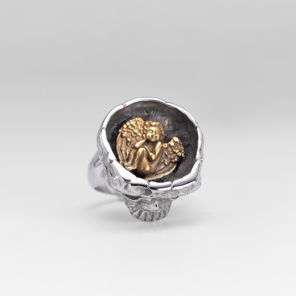 Top view of the Nick Von K Rebirth skull ring showing a gold-toned angel relief in a dark circular setting.