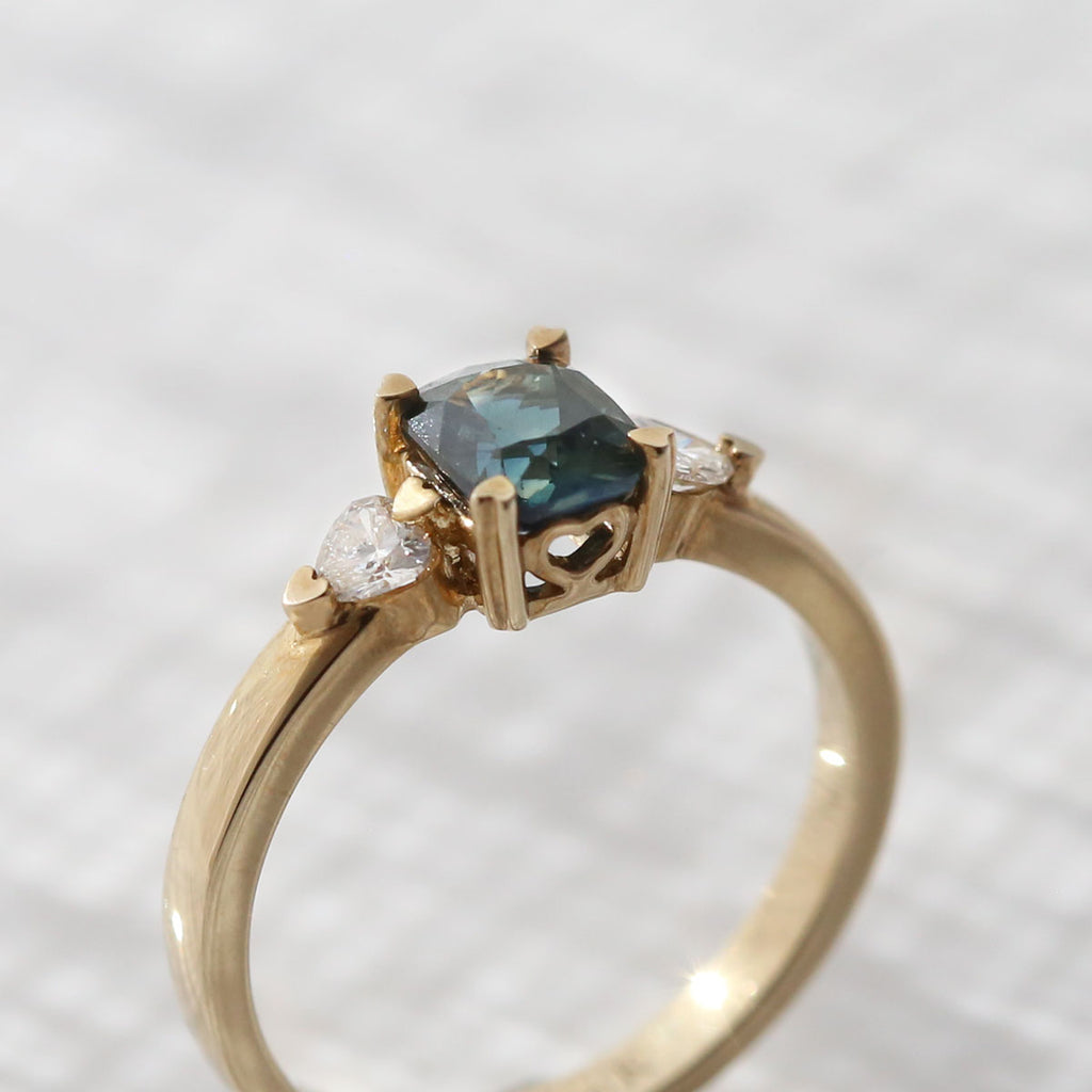 Hidden Hearts Ring with 1.40 carat Teal Parti Sapphire and heart shaped Diamonds in 9 carat Yellow Gold